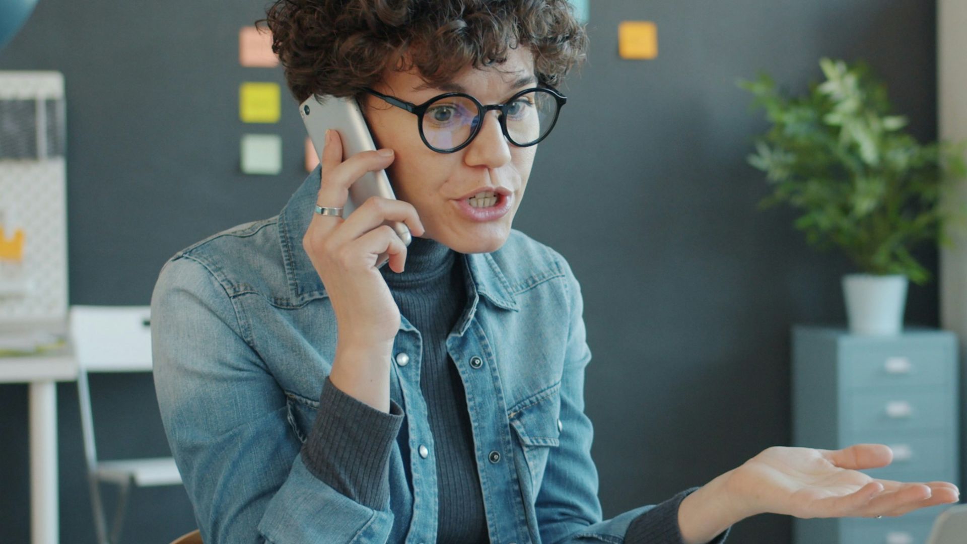 Woman talking on phone at desk with laptop.