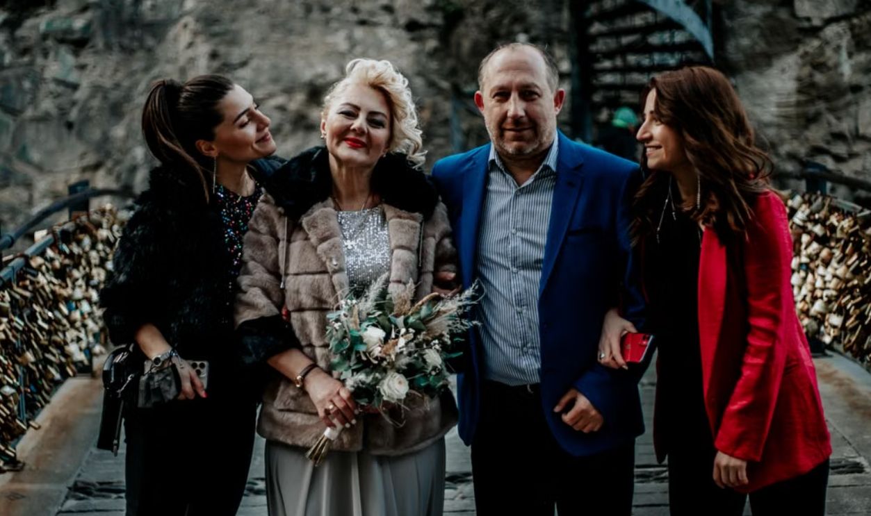 A joyful family gathering with smiling adults dressed elegantly outdoors, embracing and celebrating