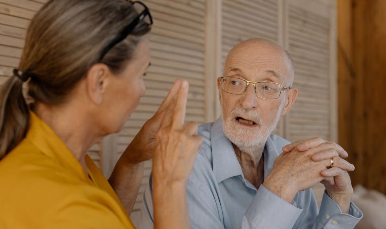 Elderly couple having an engaging conversation indoors, showcasing connection and emotion