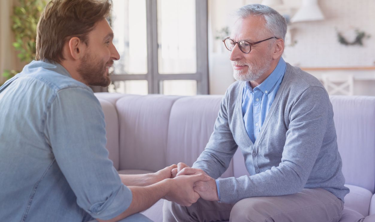 Shutterstock-2712112603, Young adult caucasian son listening and supporting his old elderly senior father at home indoors. Happy father`s day! Care and love concept. I love you, dad!