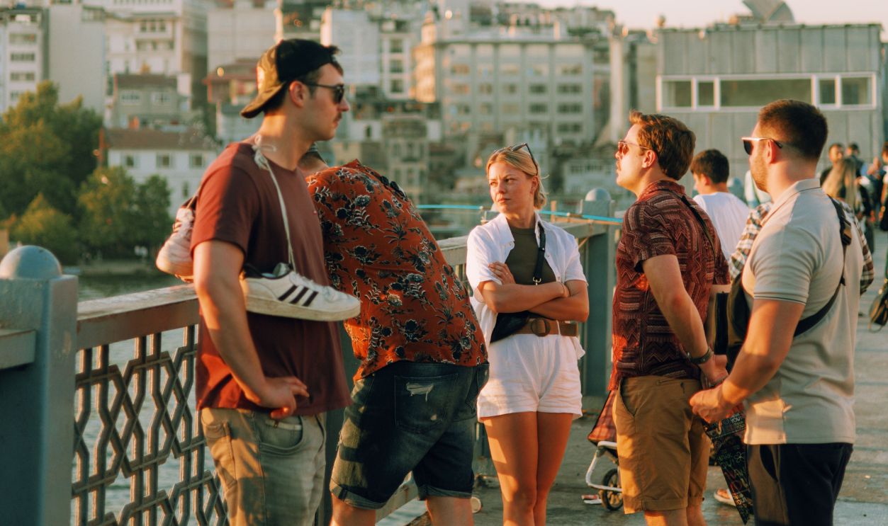 Group of young adults enjoying a sunny day on a Istanbul bridge with Galata Tower view