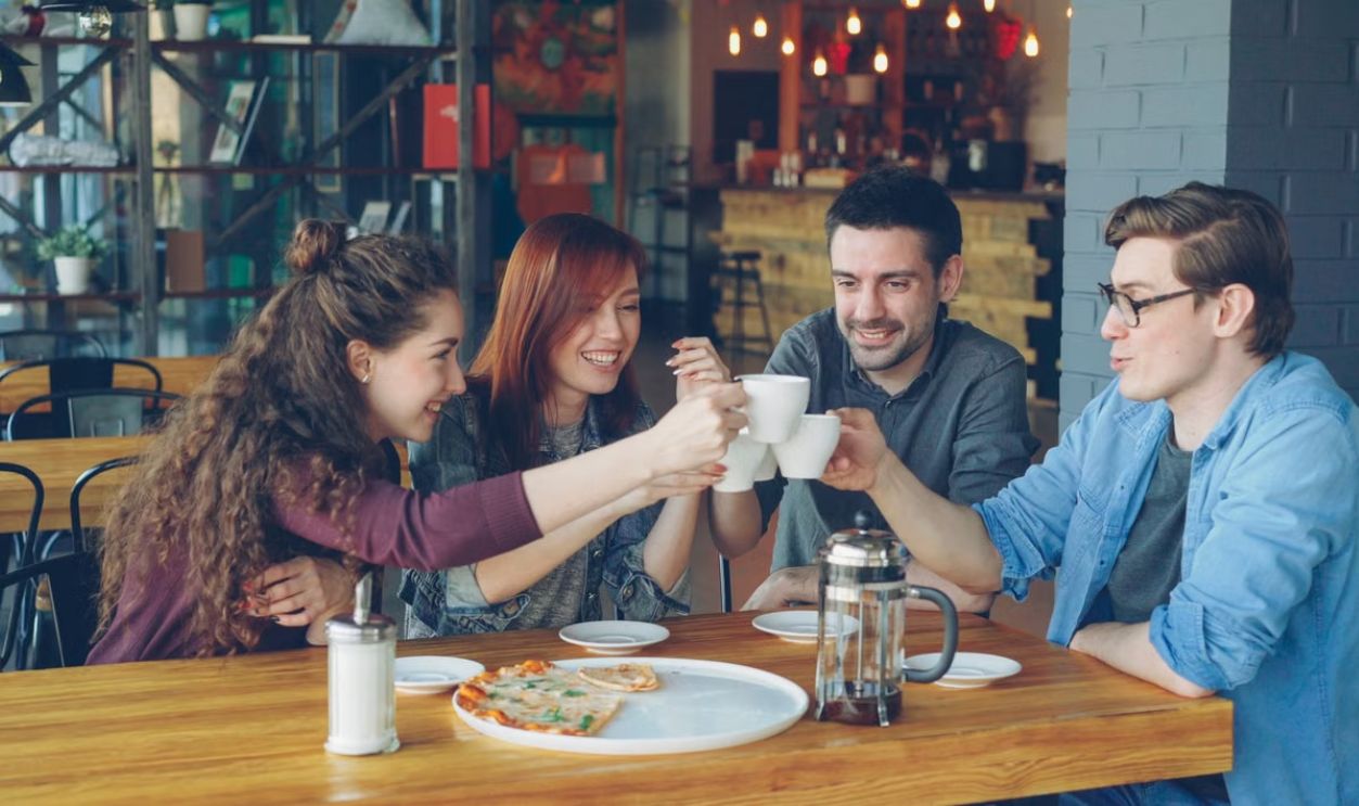 A group of friends toasting with coffee cups at a cozy café setting