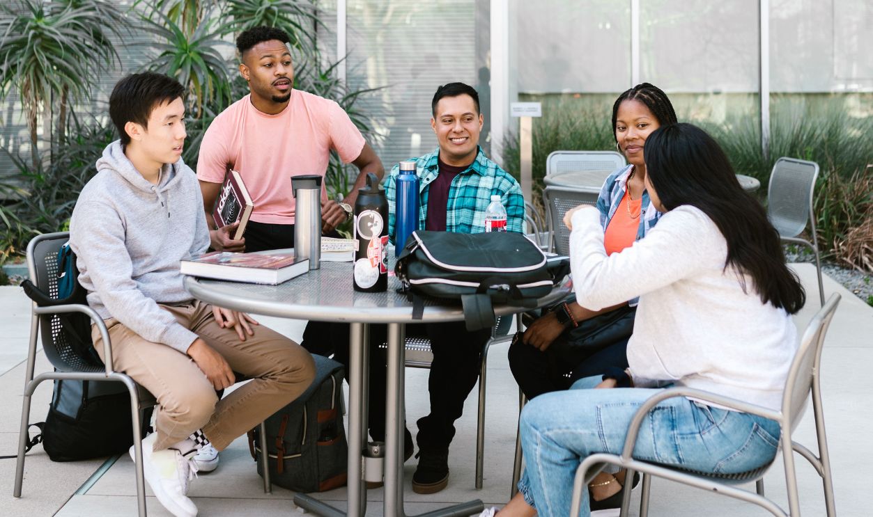 A diverse group of college students studying together outside a modern building