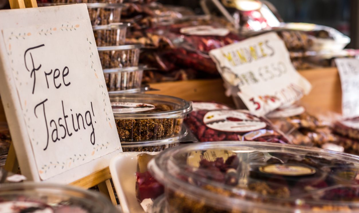 Sign saying "free tasting" among the sweets in street market