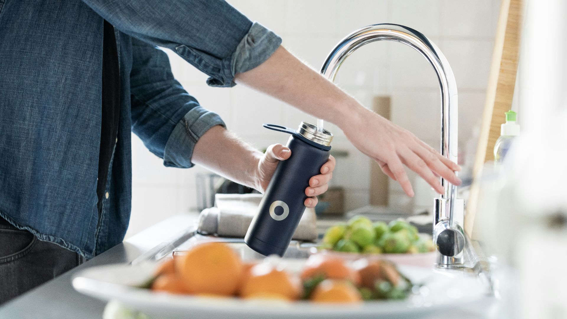 person in blue denim jacket holding stainless steel bottle