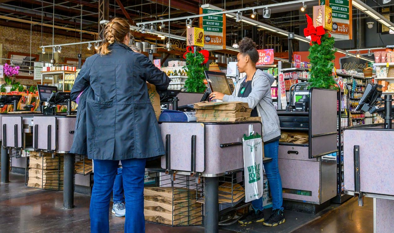 Shutterstock-2397510015, NEW ORLEANS, LA, USA - DECEMBER 5, 2023: Checkout counter with cashier and customers in the Uptown Whole Foods grocery store
