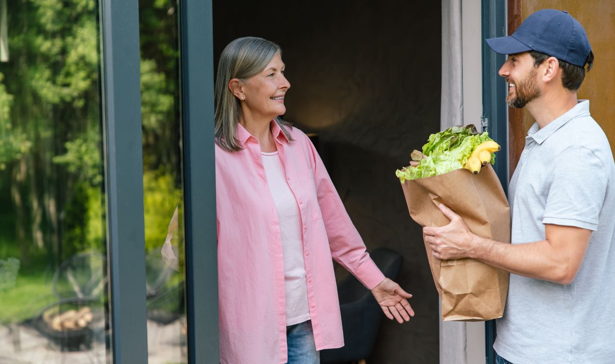 Grocery store delivery man delivering food to woman home.