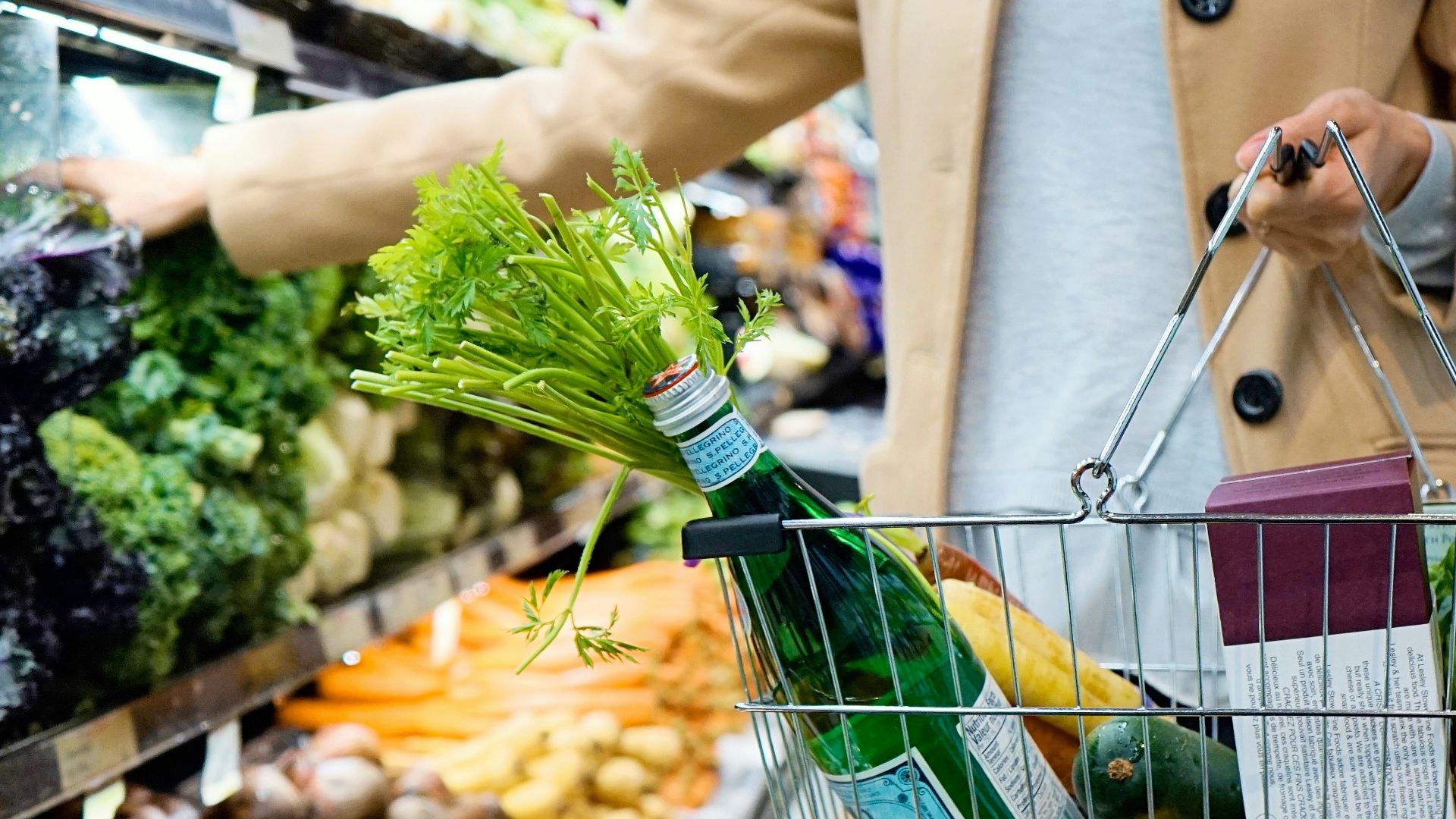 woman in white coat holding green shopping cart