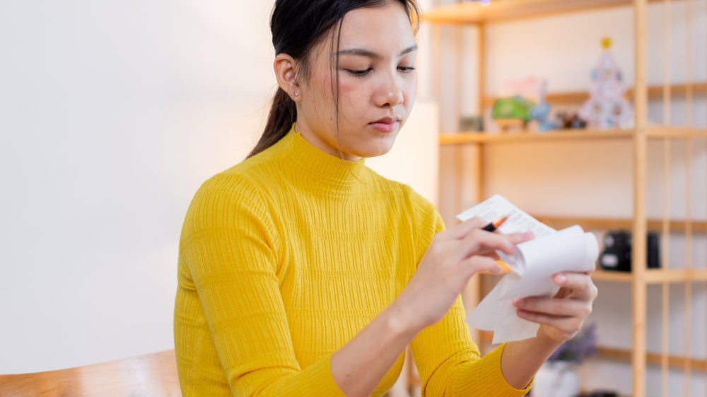 Stressed young asian woman calculating monthly home expenses