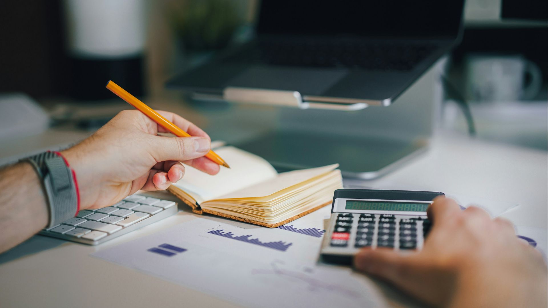 a person sitting at a desk with a calculator and a notebook