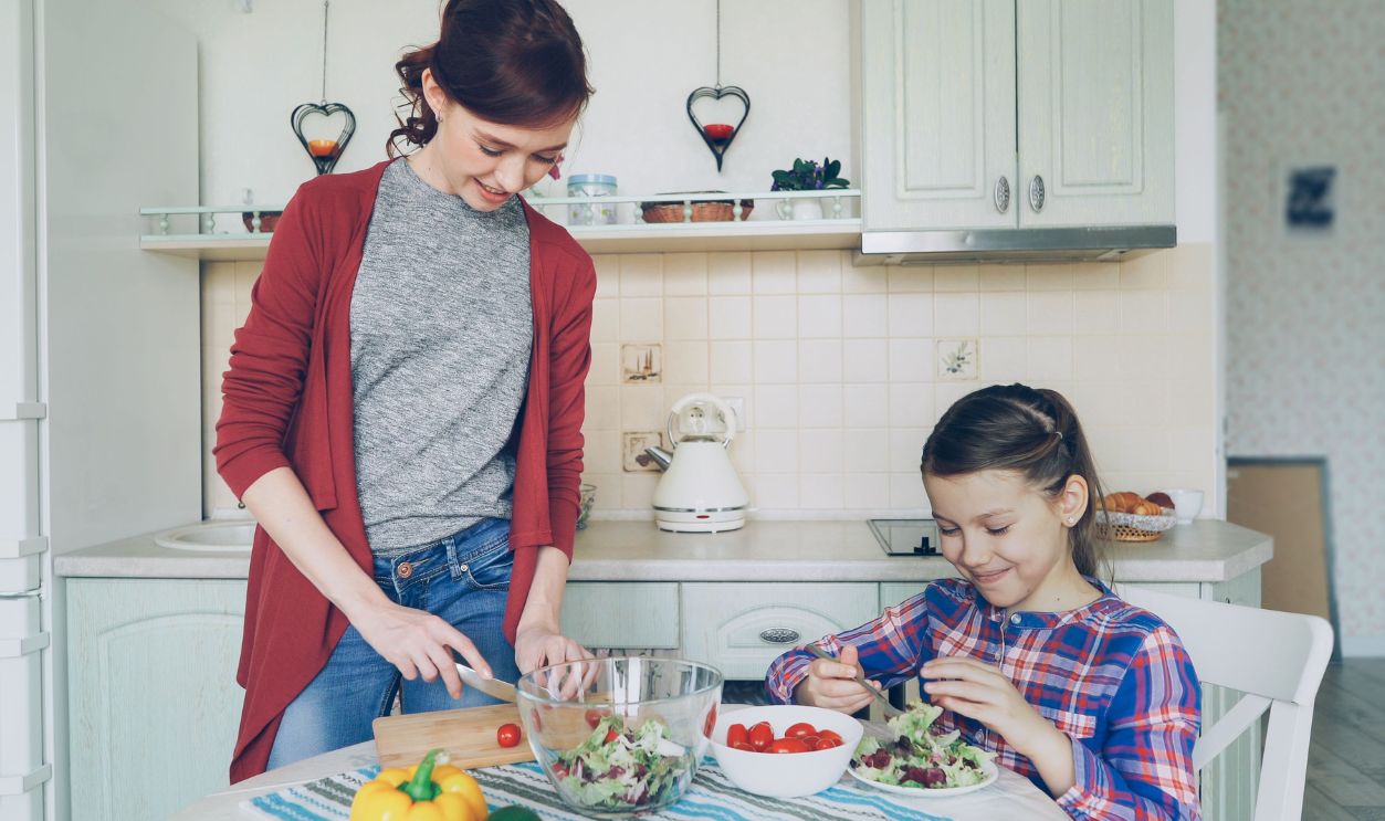 A mother and daughter enjoy preparing a fresh salad together