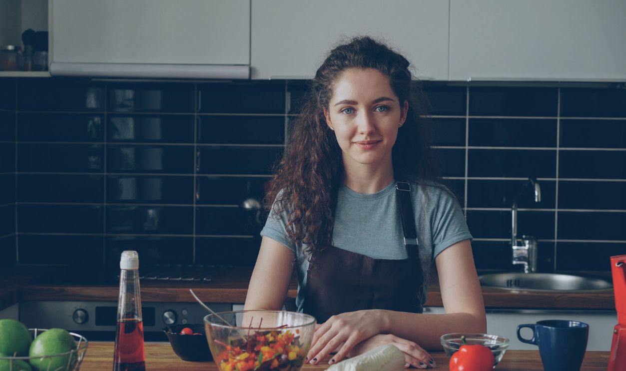 A young woman stands confidently in a modern kitchen