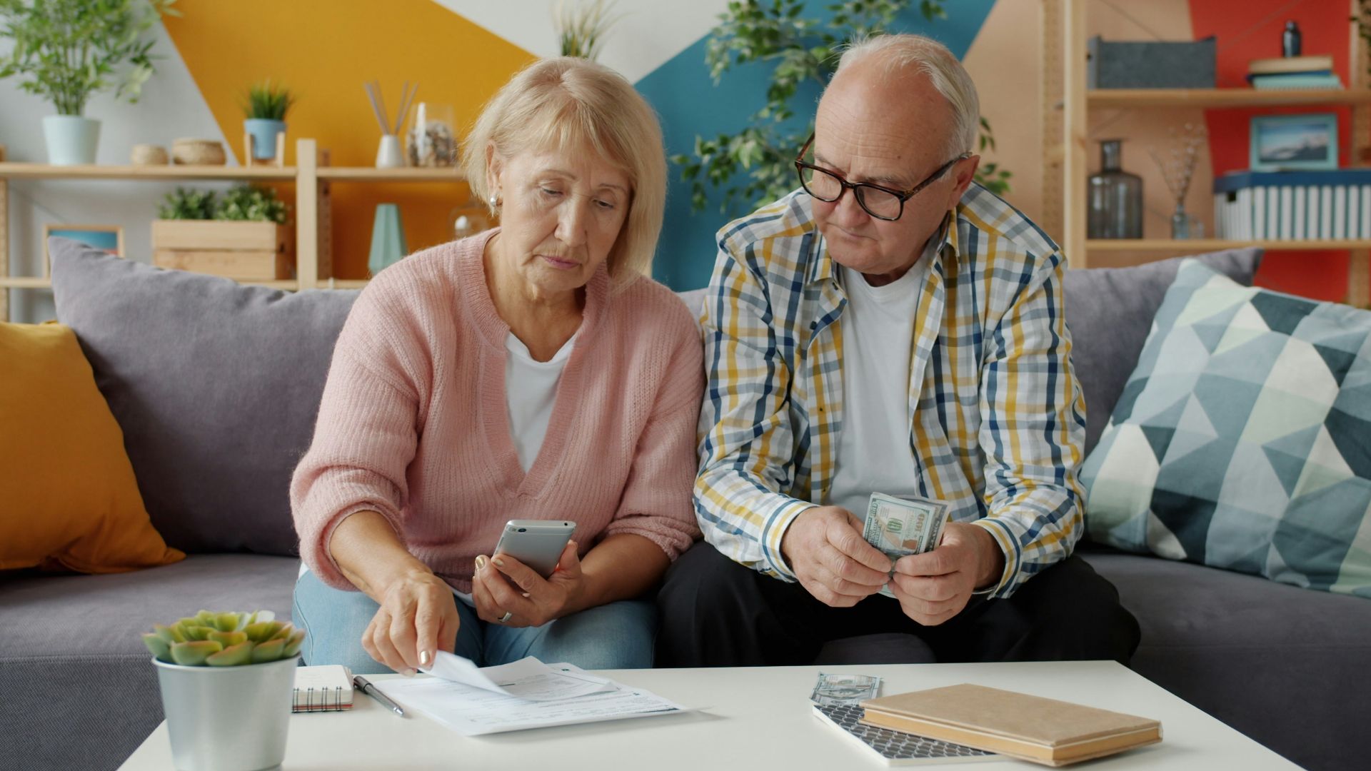 Elderly couple looking at bills and phone