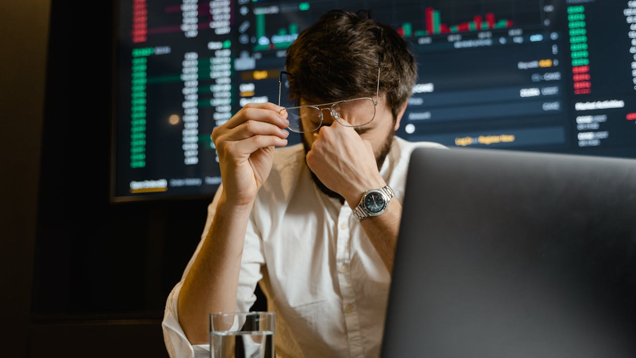 Man in White Dress Shirt Using Black Laptop Computer looking at stock market.