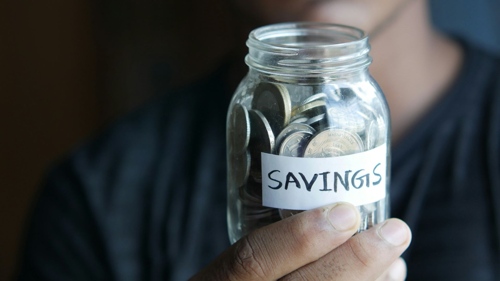 a man holding a jar with a savings label on it