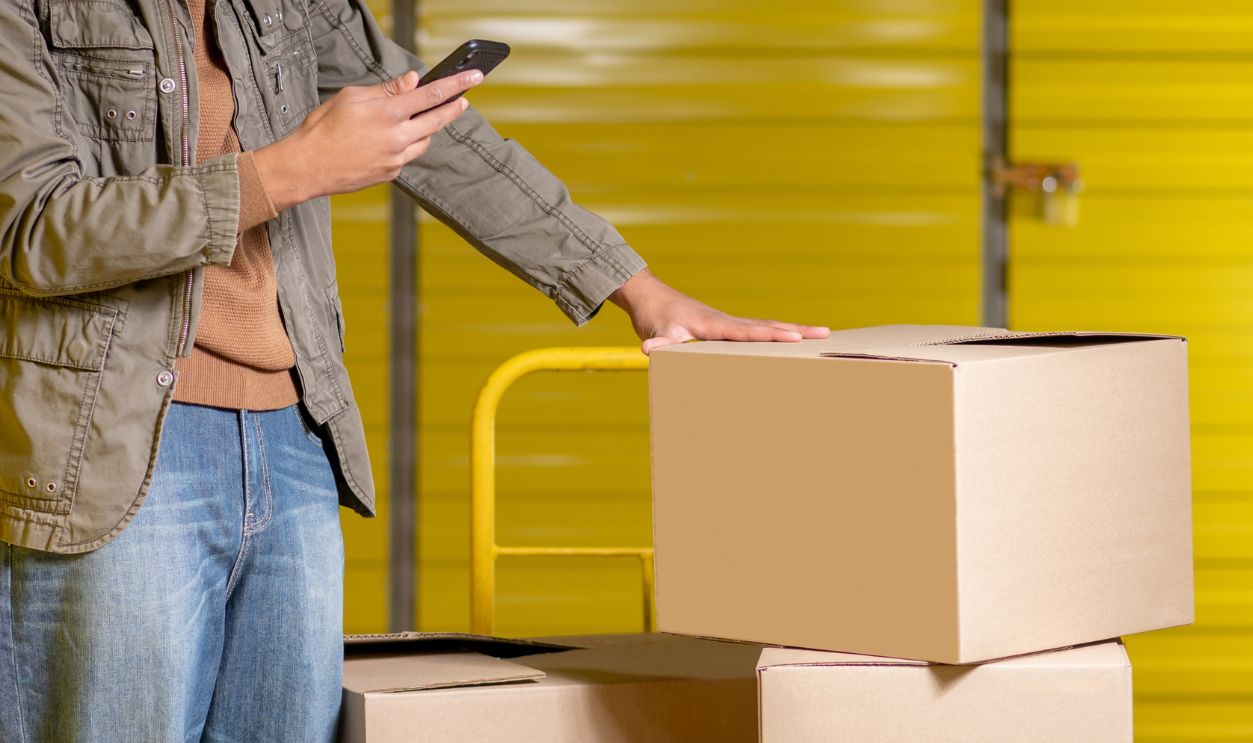 Curly-haired young service man making picture of the boxes
