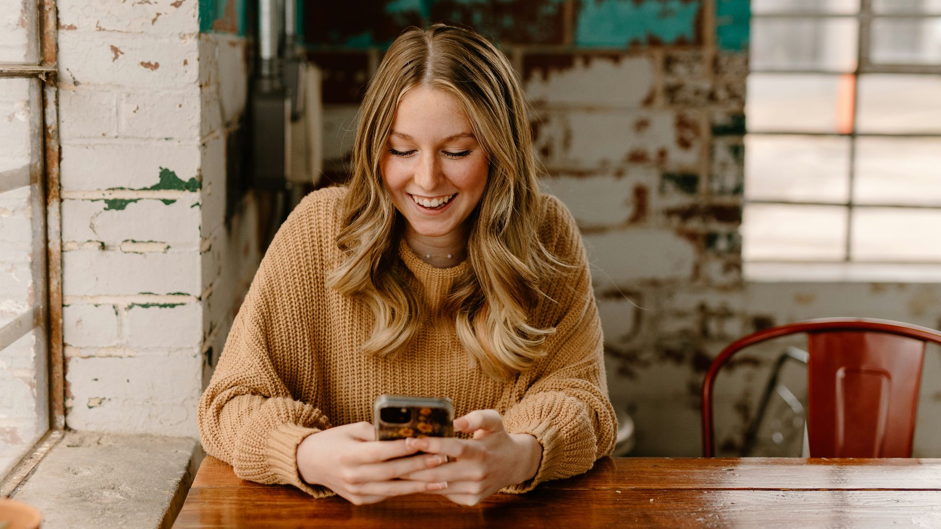 a woman sitting at a table looking at her cell phone