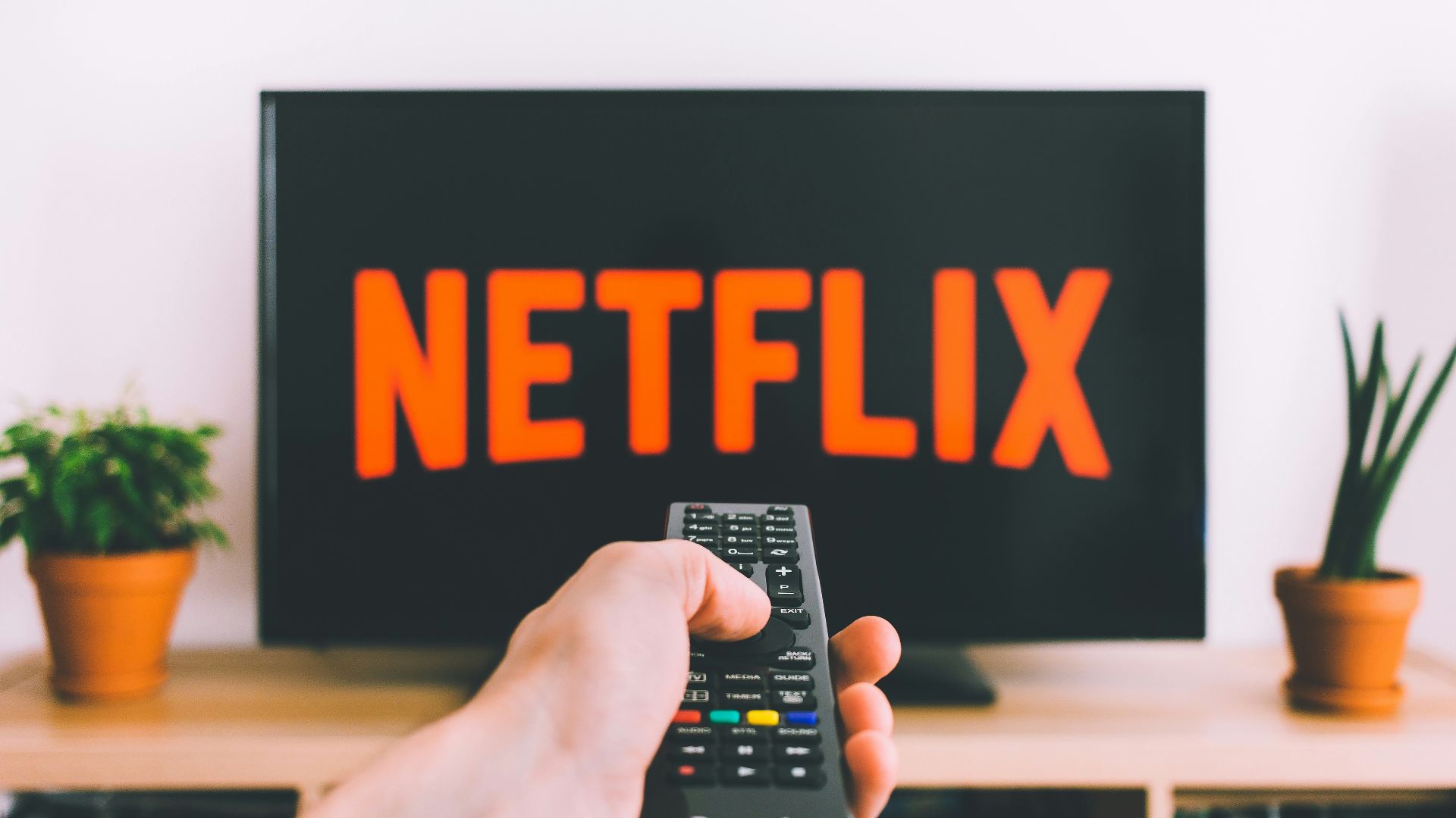 person holding remote pointing at TV