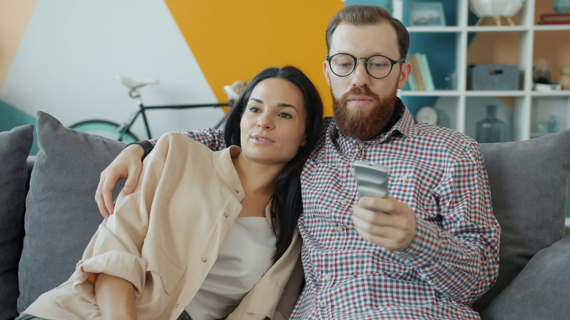 Couple sitting on couch, man holding credit card.