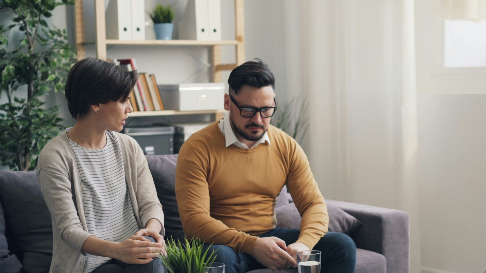 a man and woman sitting on a couch talking to each other