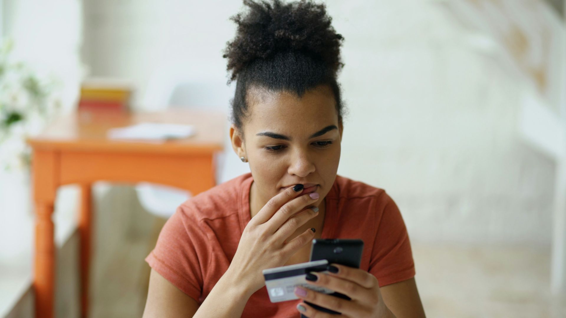 Woman looking at phone with credit card in hand