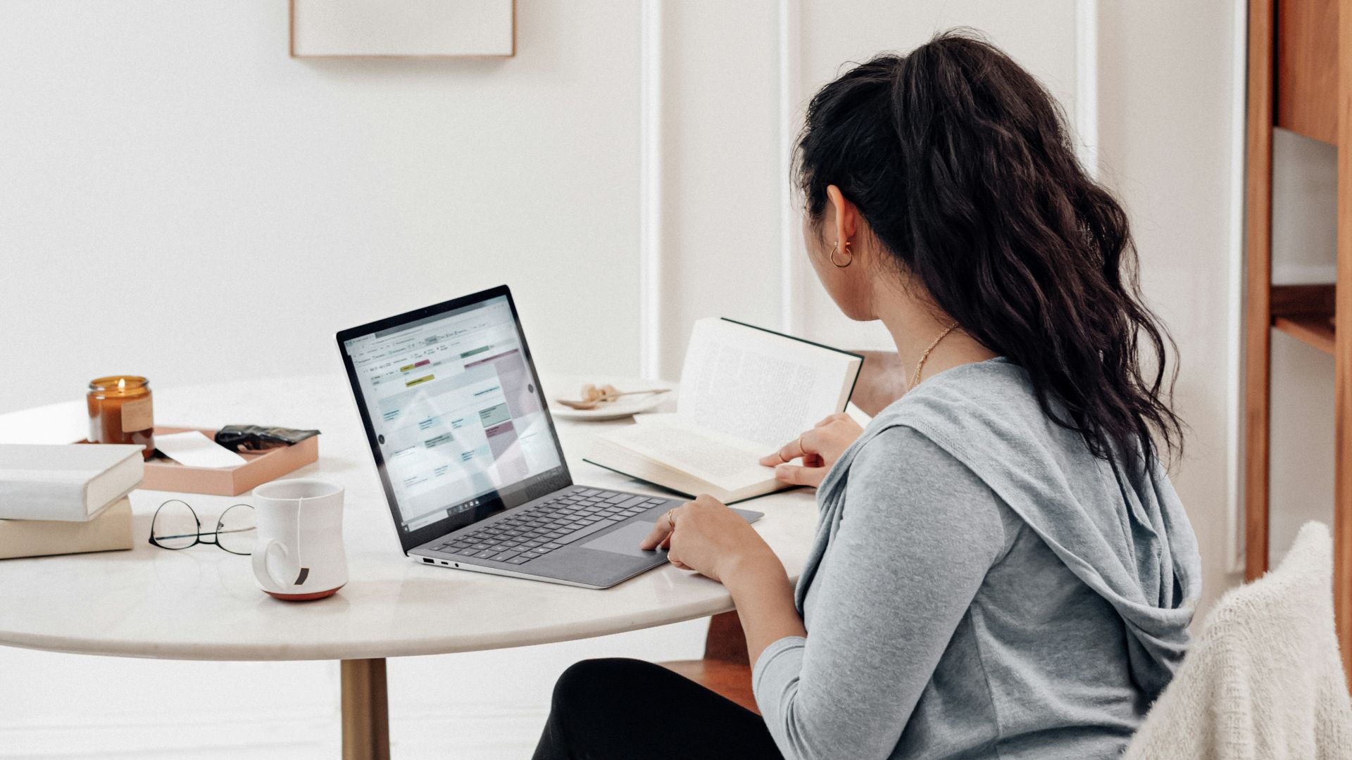 woman in gray sweater using microsoft surface laptop