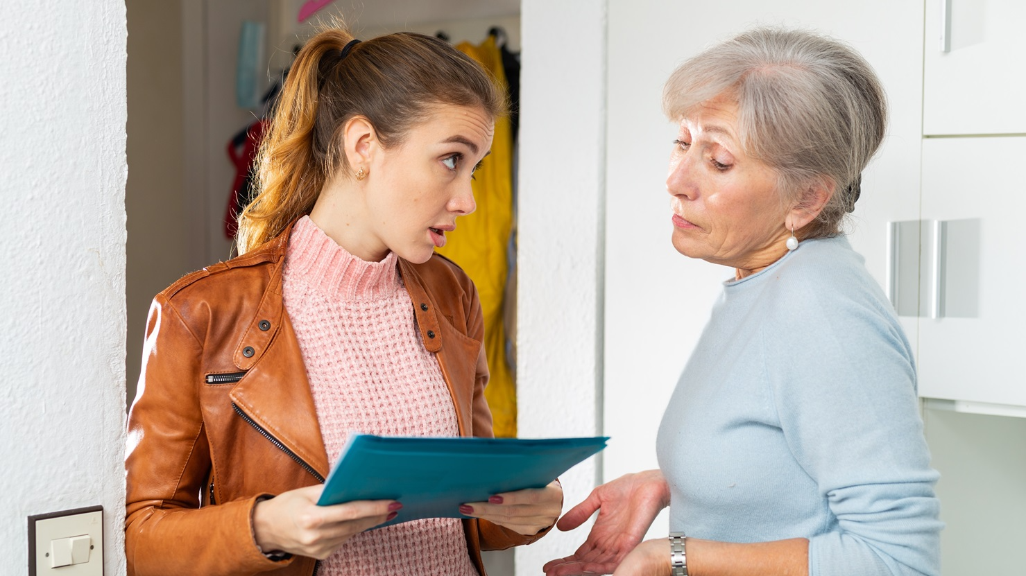 Senior and younger women standing at home and quarreling about breach of rent contract.