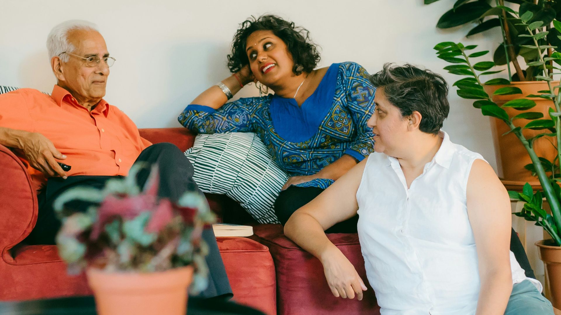 a woman sitting on top of a red couch next to a man