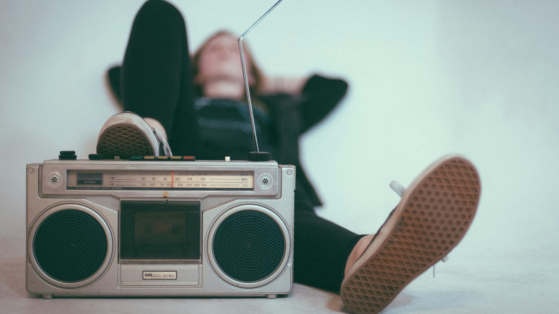 woman laying on bed near gray radio