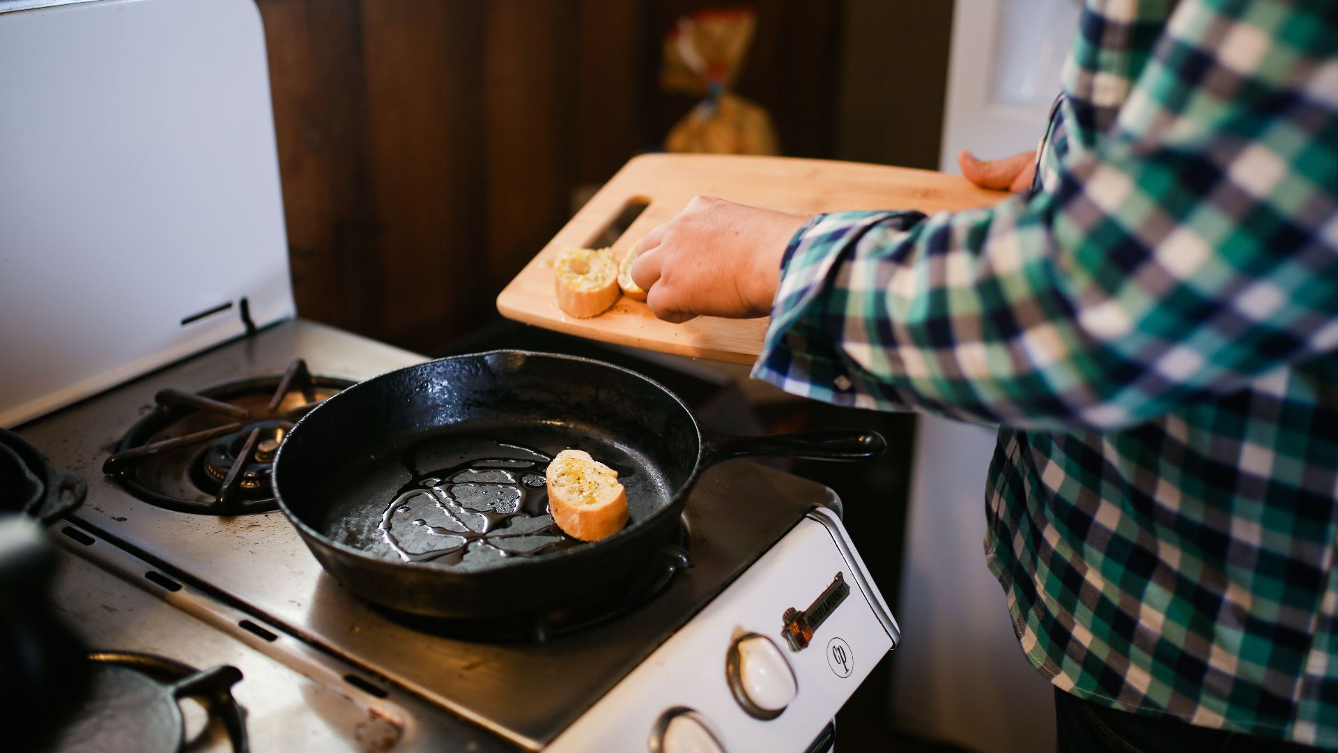 Person cooking with skillet on stove, preparing a delicious meal. Cozy kitchen atmosphere.