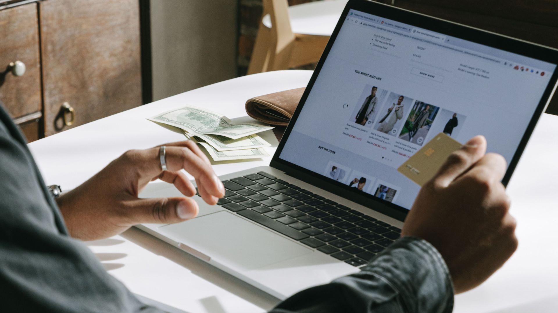 An adult uses a credit card for online shopping on a laptop indoors.