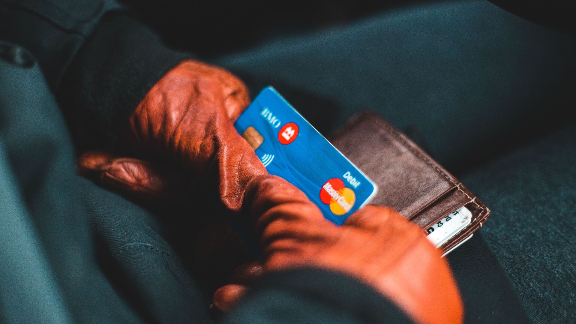 Close-up of hands in gloves holding a credit card and wallet indoors.