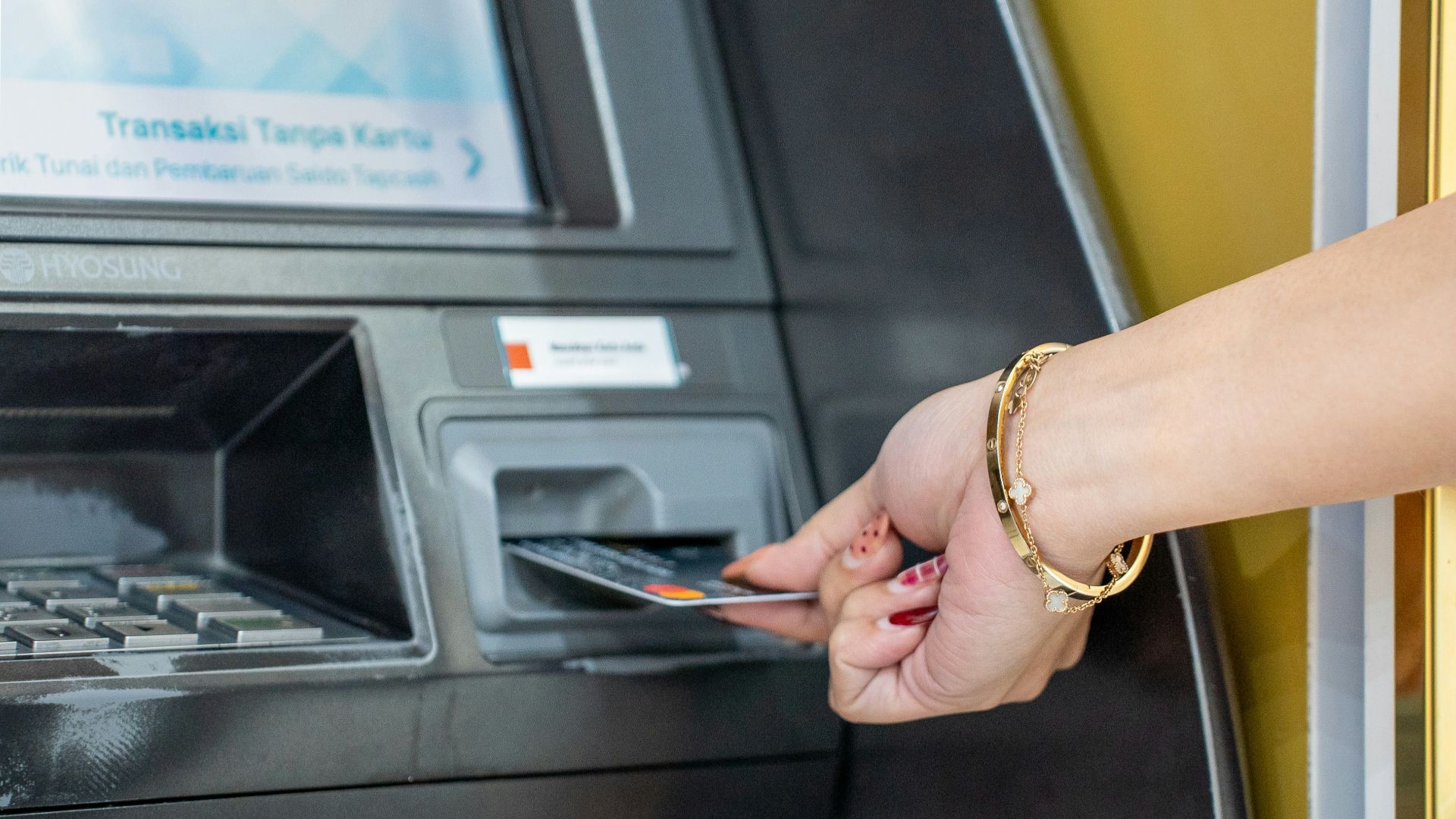 A hand inserts a card into an atm machine.