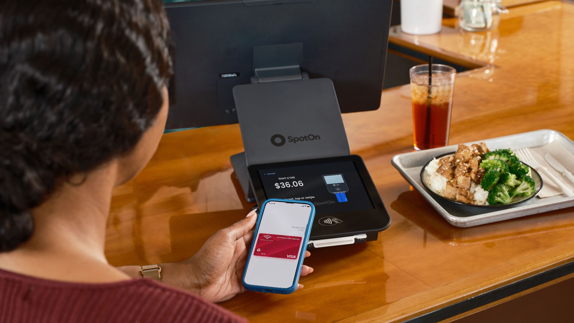 A customer uses mobile payment at a restaurant counter with SpotOn POS.