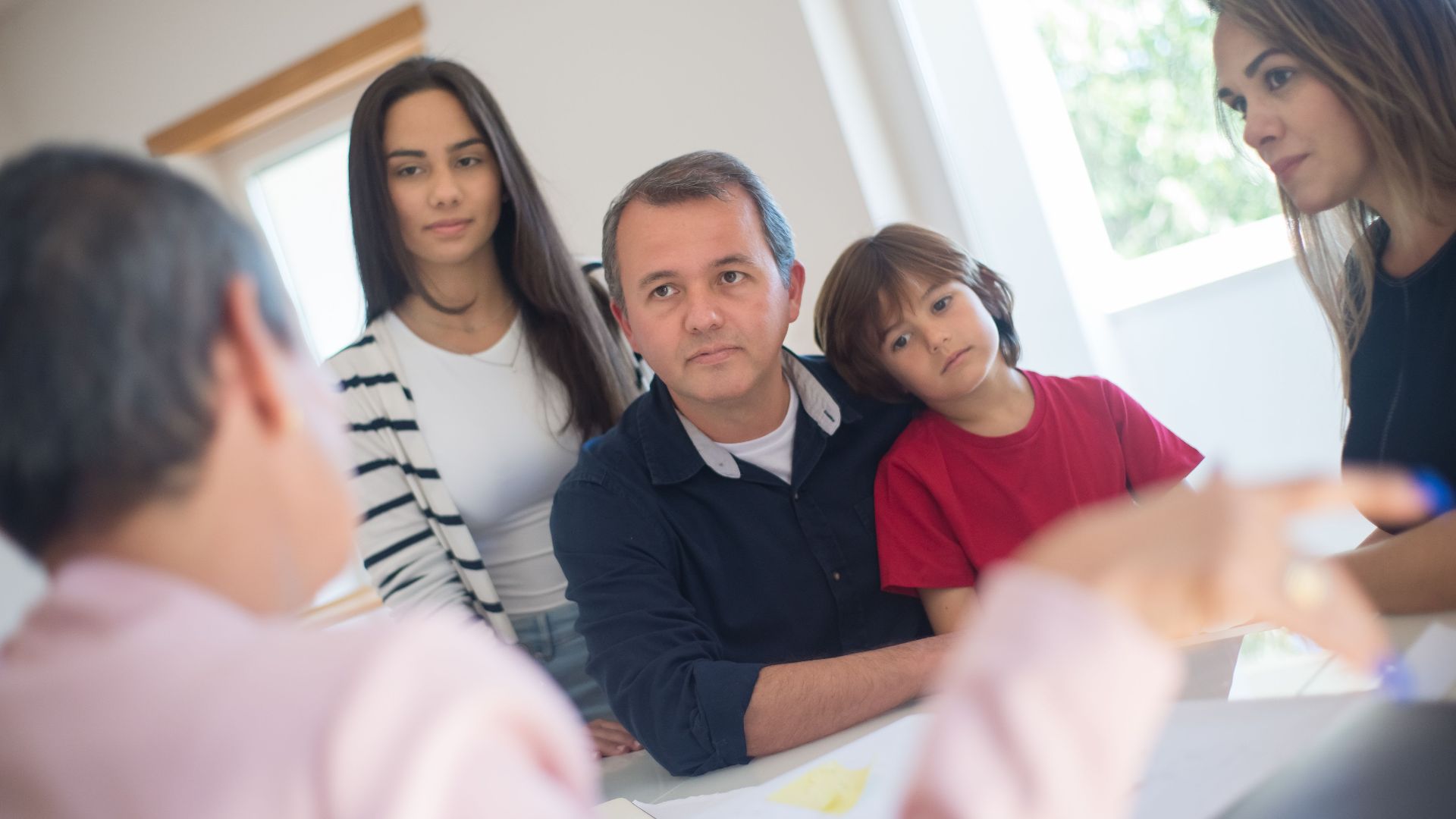 A family of four seeks advice from a professional during an indoor consultation in a bright room.