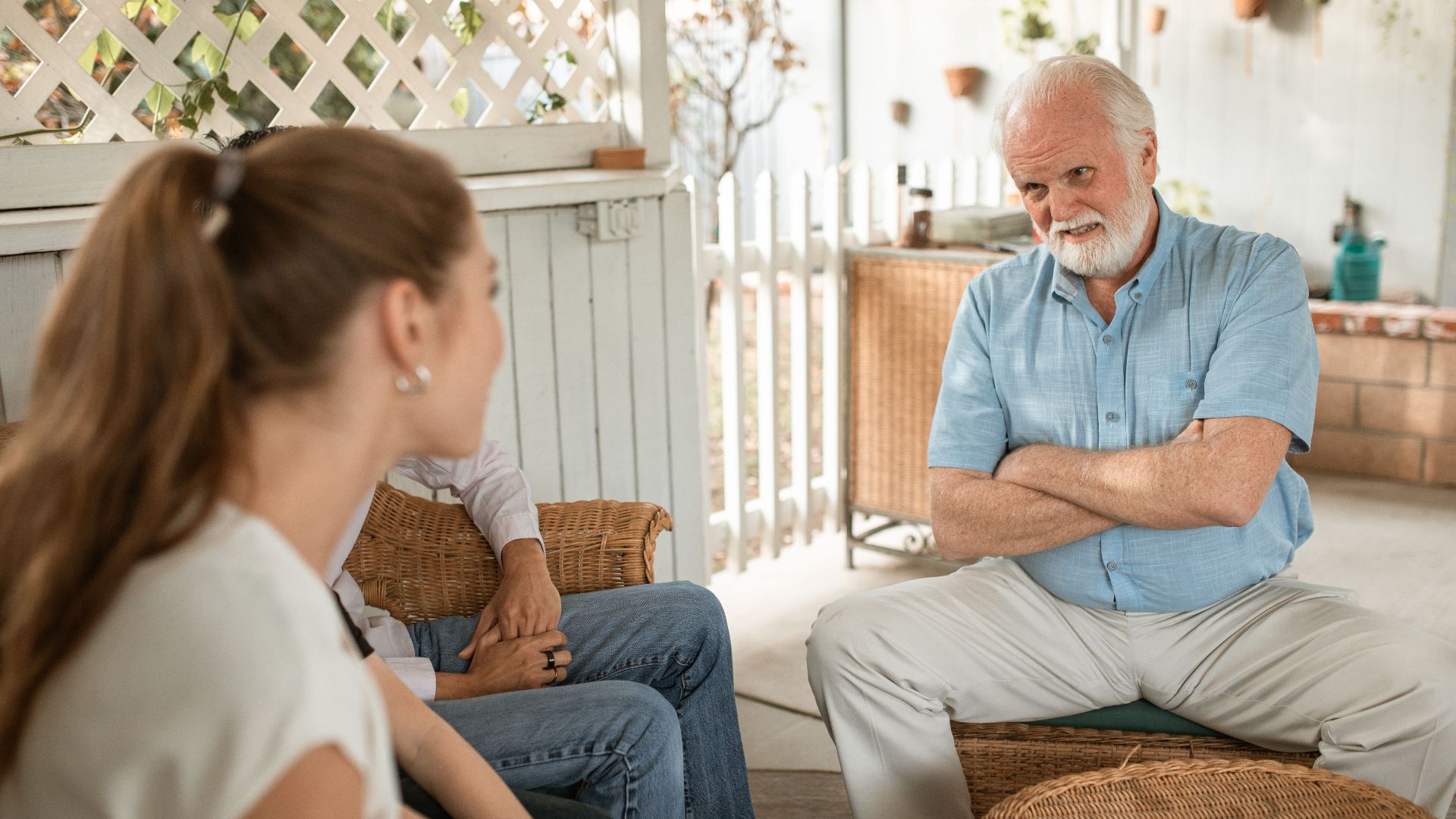 Senior man and two adults having a friendly conversation on a spacious veranda.