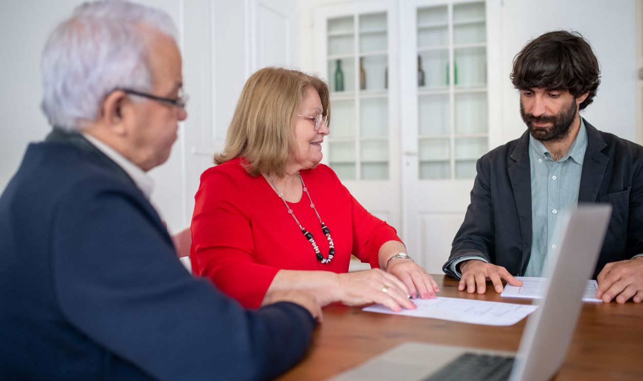 Three business professionals in a meeting, discussing documents and planning strategies indoors.