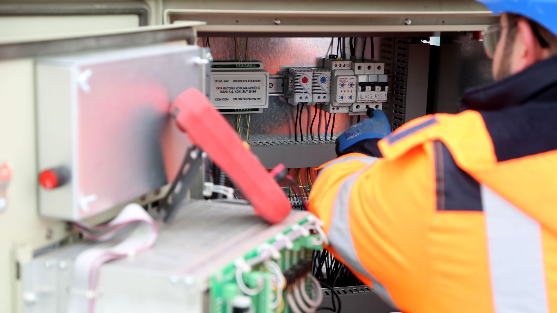 Professional engineer inspecting industrial electrical circuit board, ensuring safety standards.