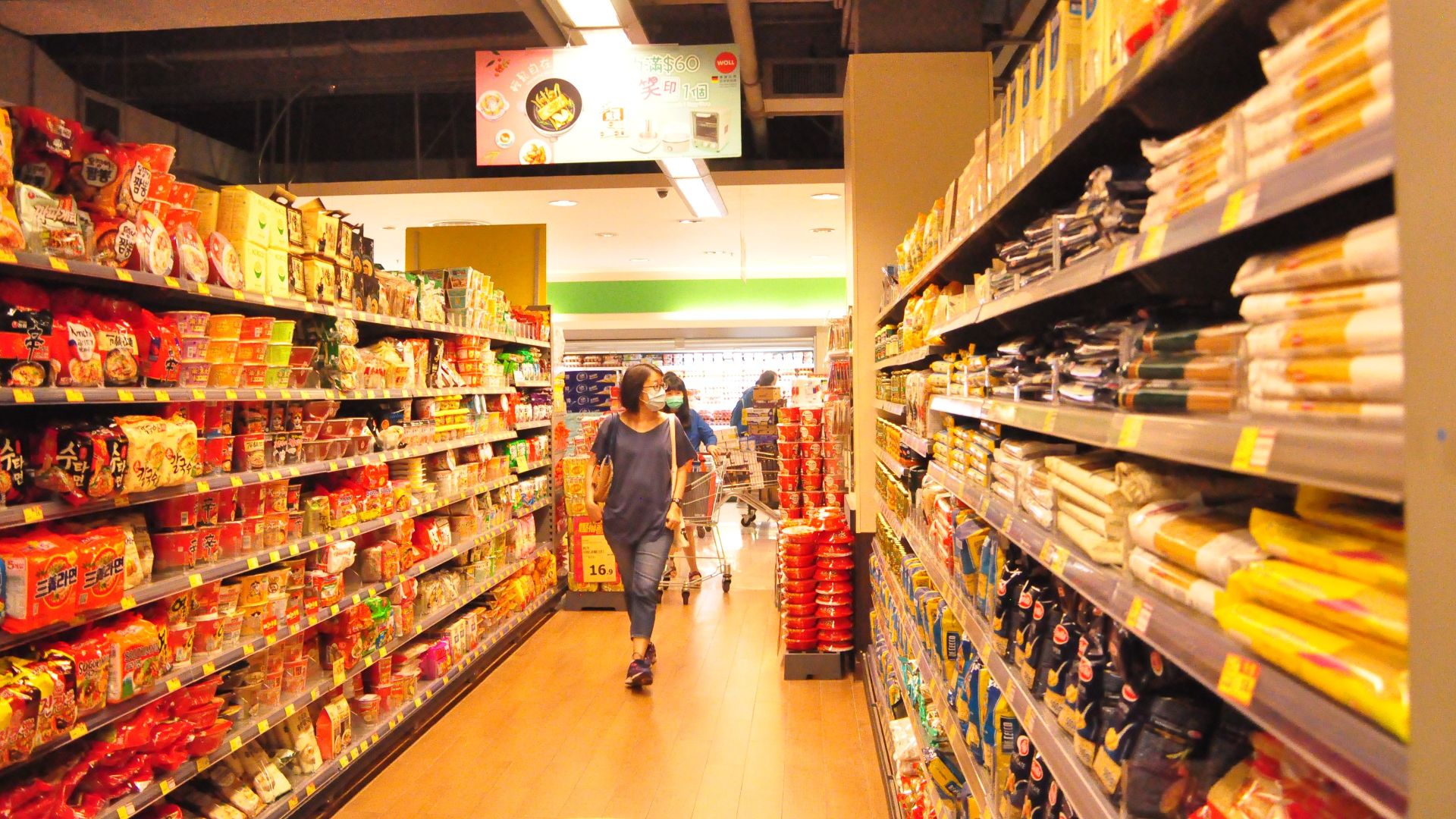 Shelves with assorted food products and customers choosing food while walking in protective masks