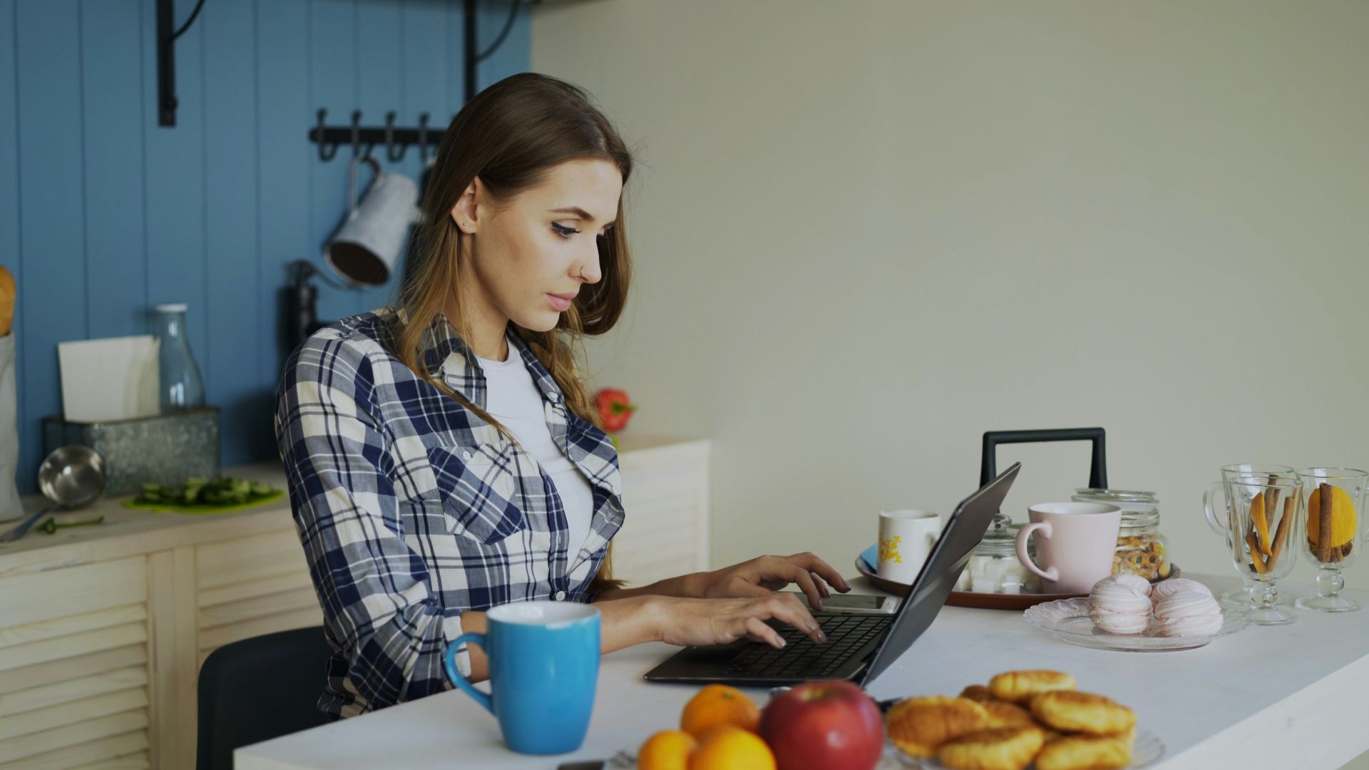 Woman working on laptop in a bright kitchen