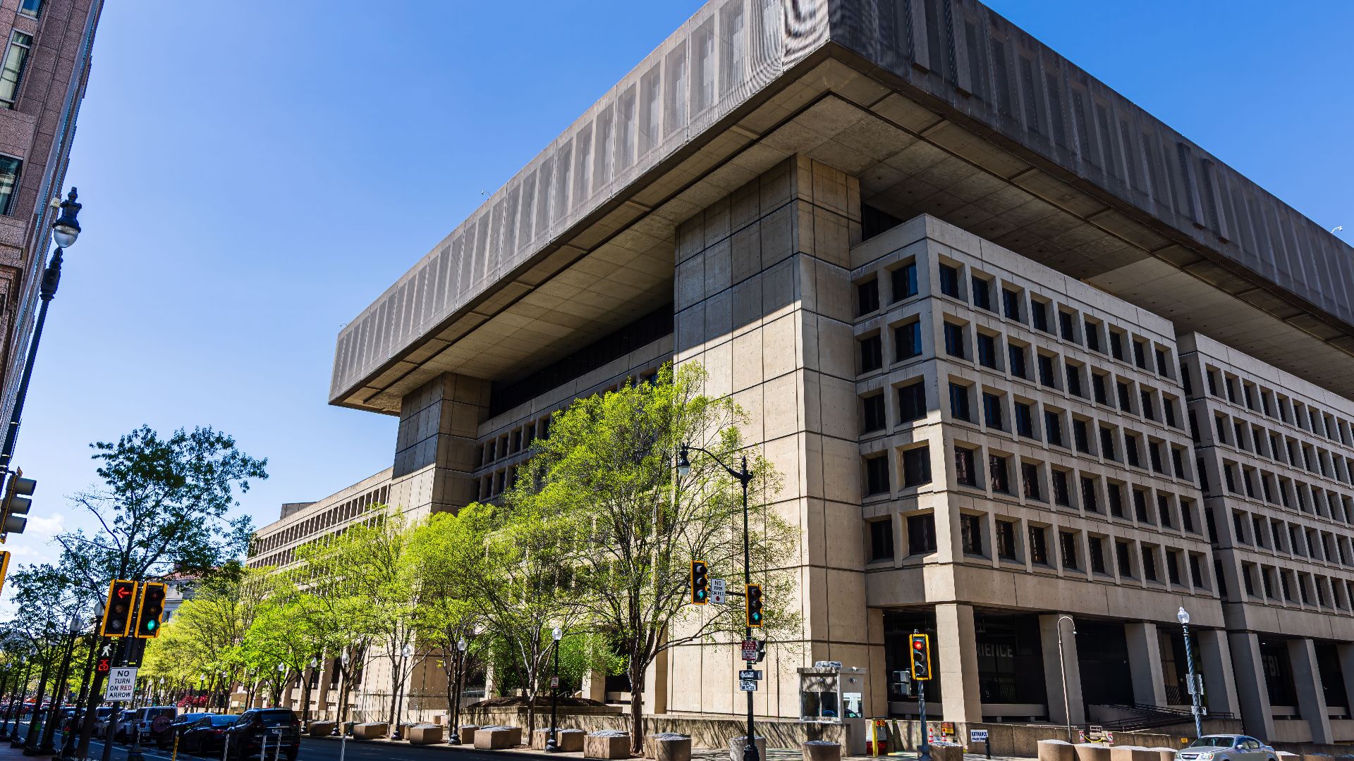 Photo of a modernist government building with a distinct overhang, taken on a sunny day with clear blue skies.