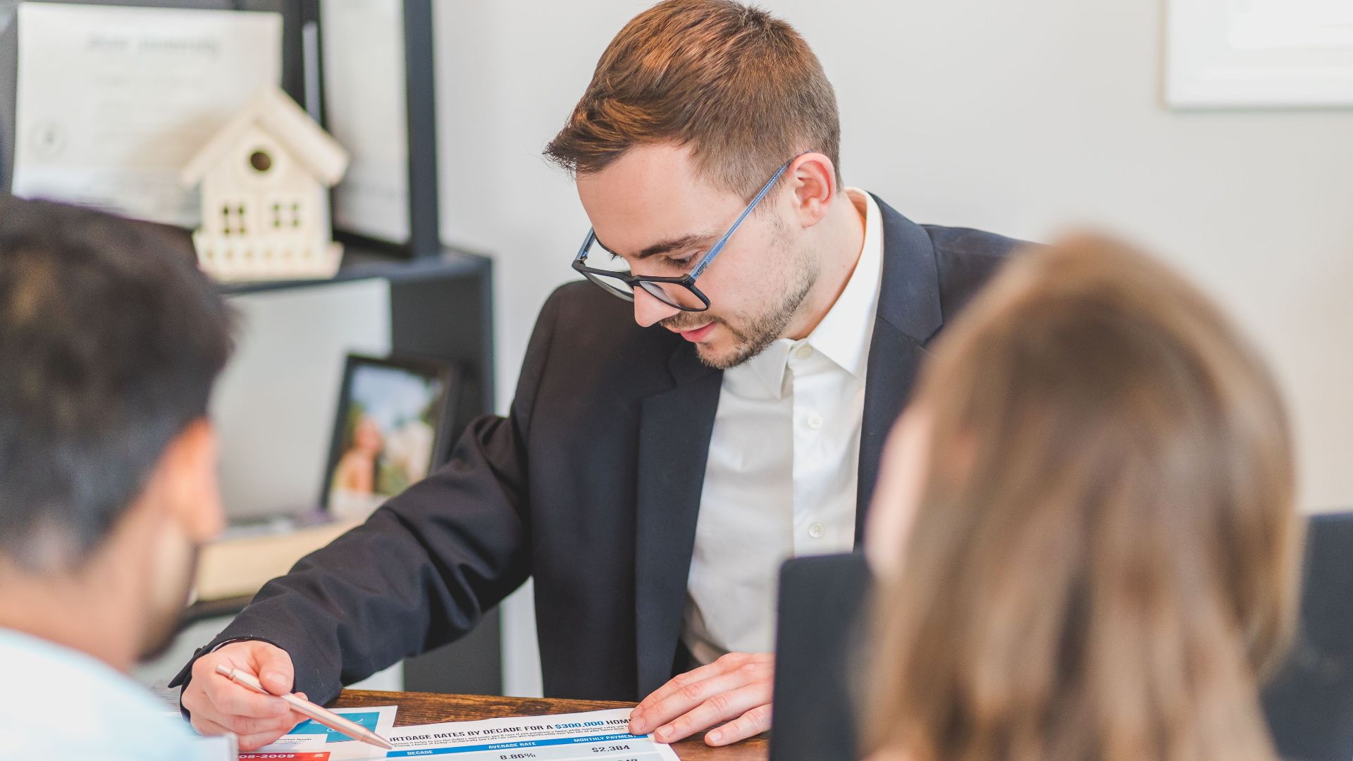 A real estate agent explains mortgage options to clients in an office setting.