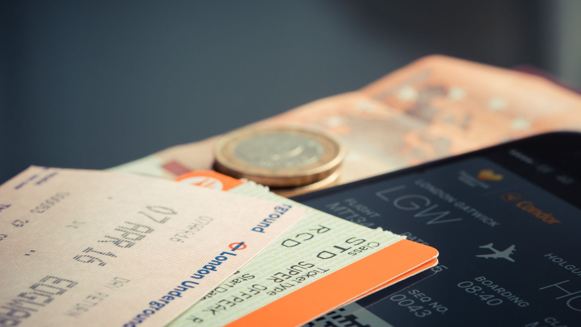 Airline ticket with euro coins and smartphone displaying flight details.