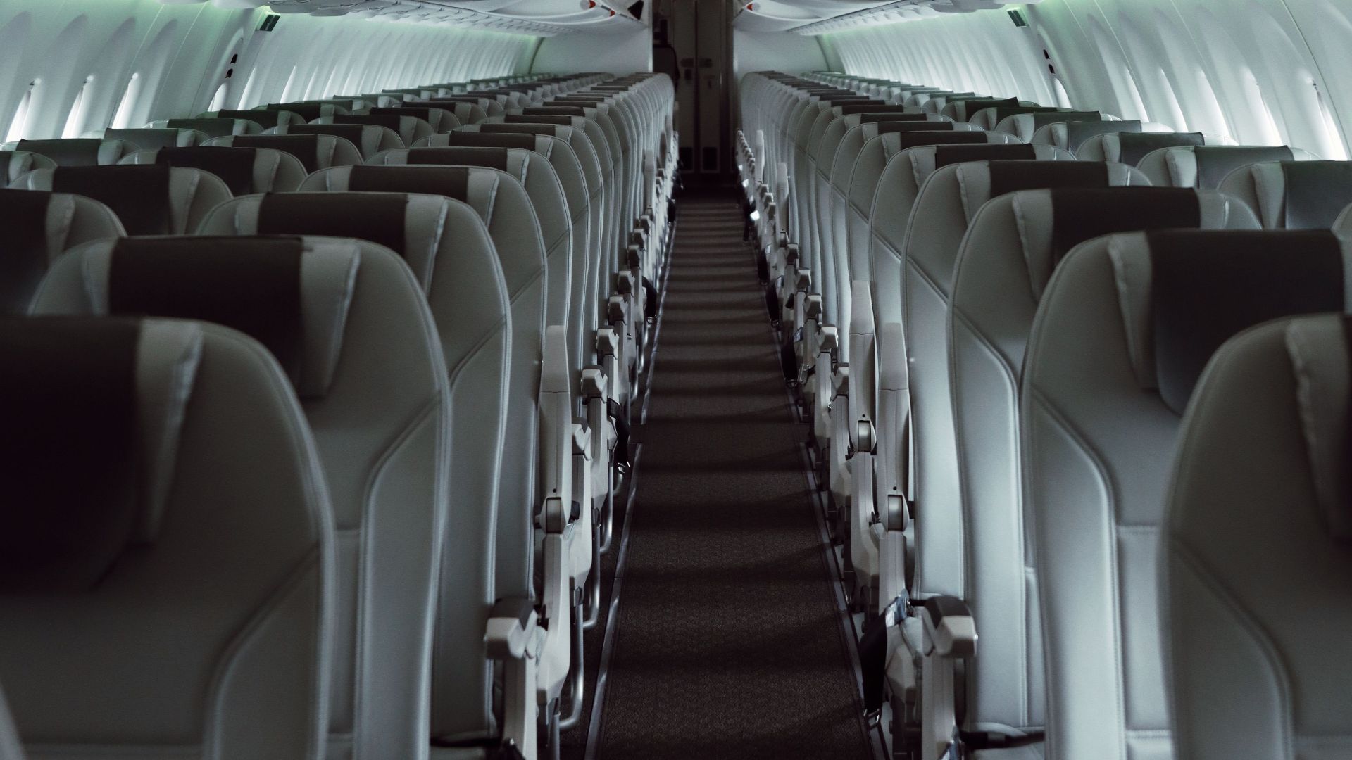 A sleek view of an empty airplane cabin showcasing modern interior design and lighting.