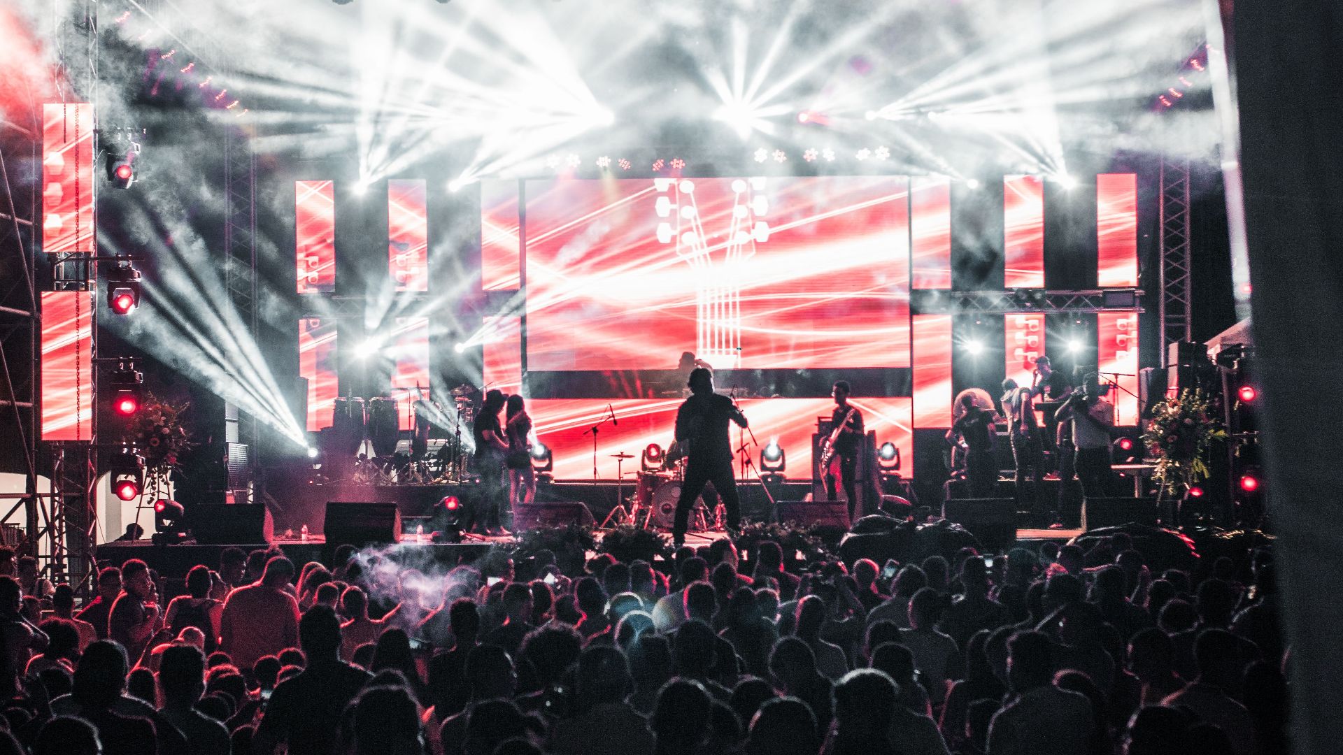 Energetic live music concert featuring performers on a vibrant stage, captivating a large audience.