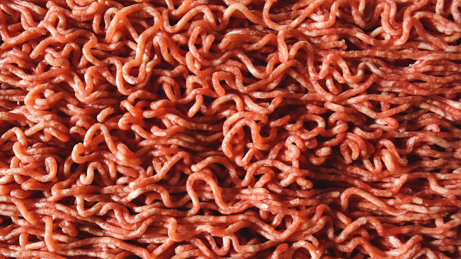 Detailed close-up image of raw, red ground beef with visible strands.