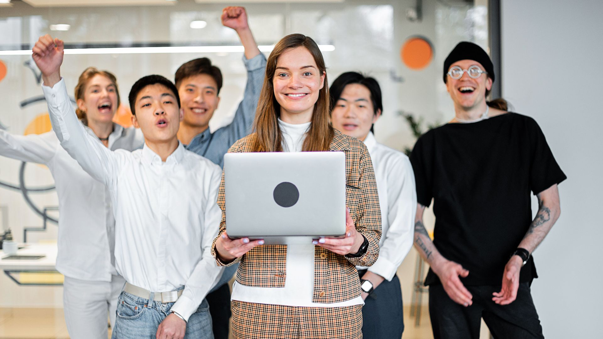 A cheerful, diverse team celebrates success in a modern office environment.