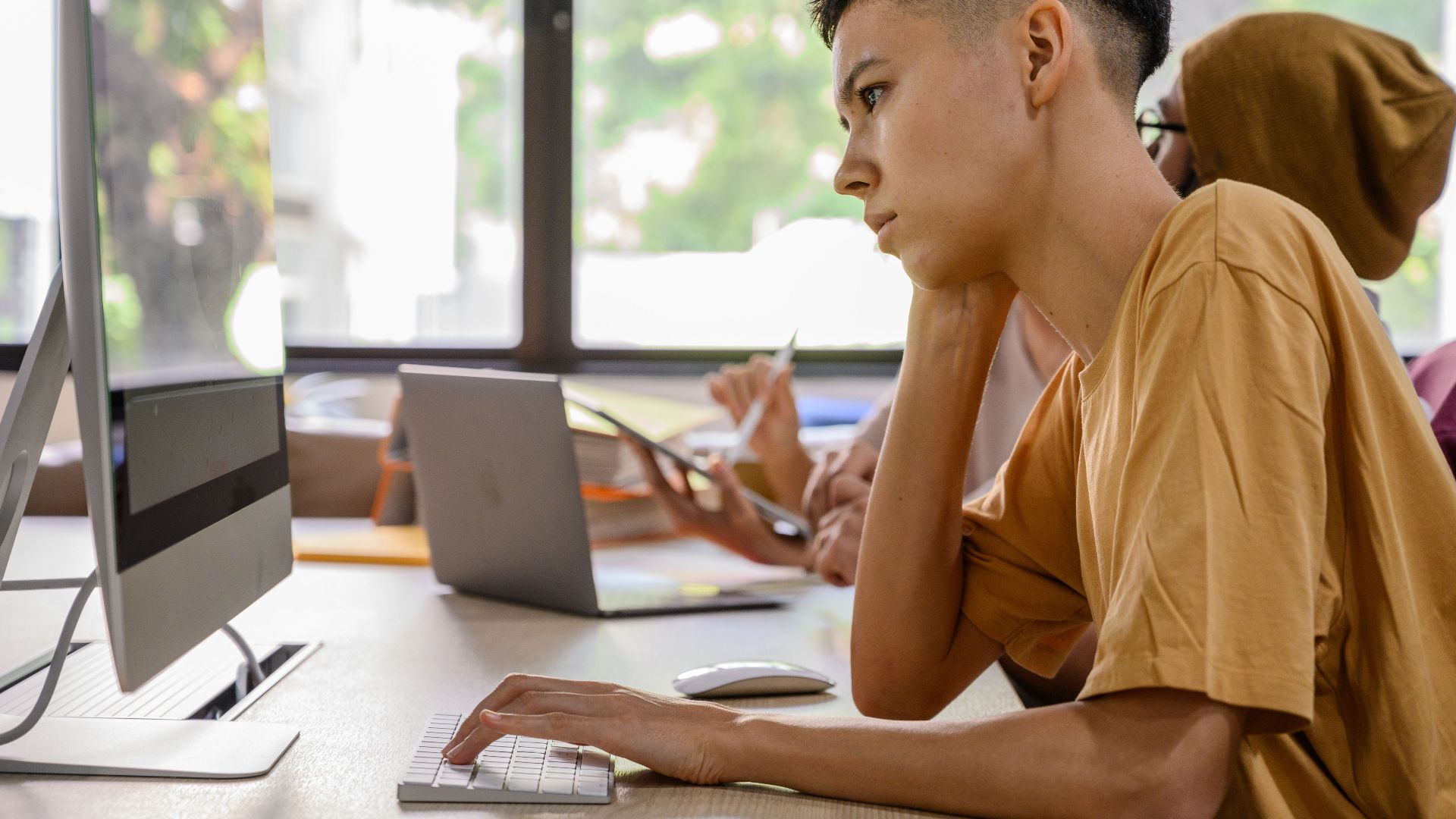 Young adults working intently at computers in an office setting.
