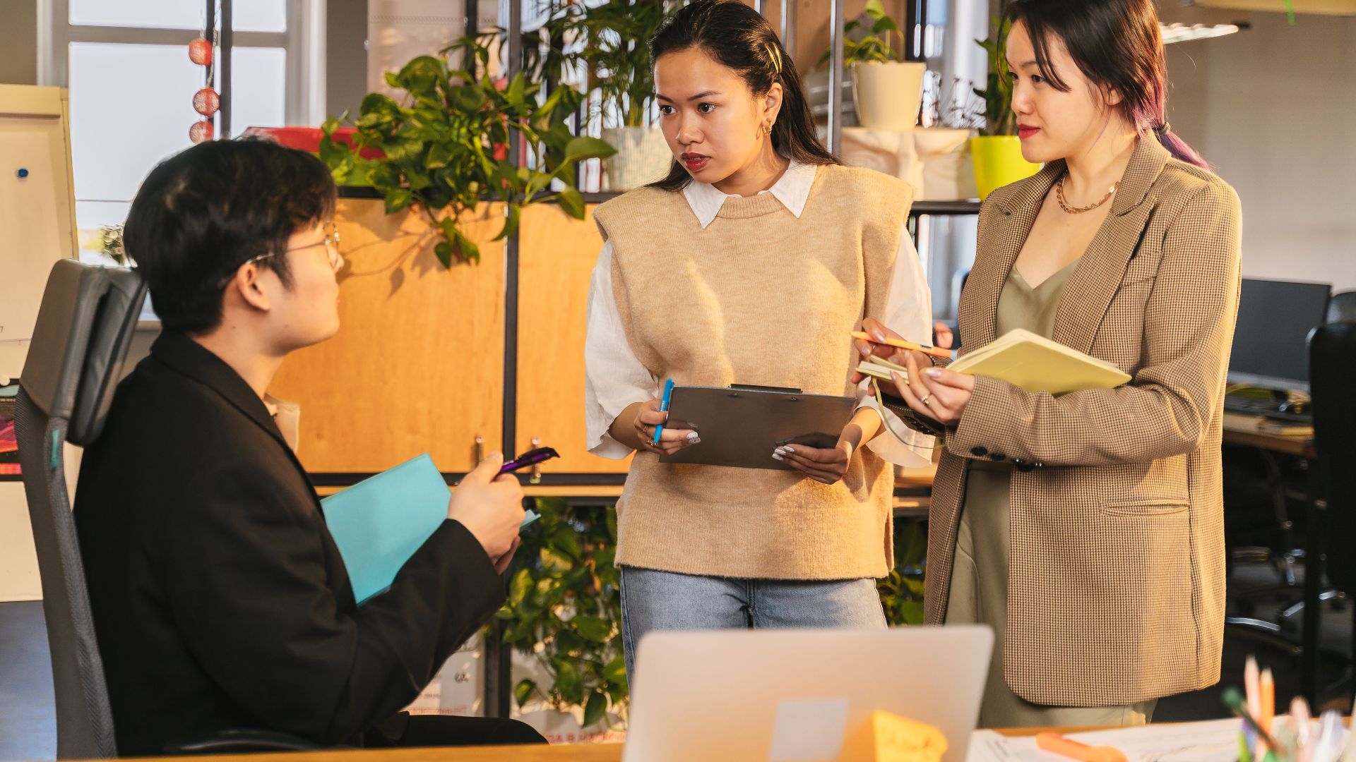 Three colleagues engaging in a discussion at a contemporary office setting.