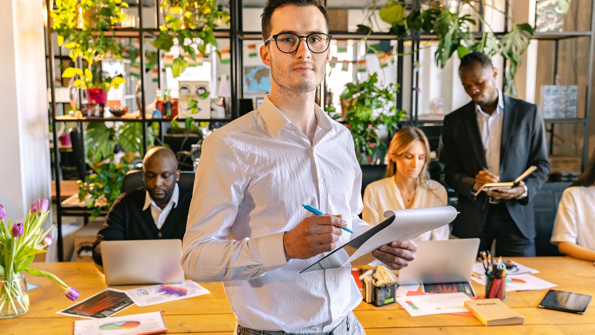 A team working collaboratively in a contemporary office space with tech gadgets and plants.